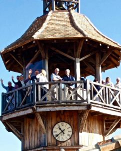 A group of visitors standing on the wooden balcony of a tower at a Bordeaux vineyard, enjoying panoramic views during a Graves wine tour.